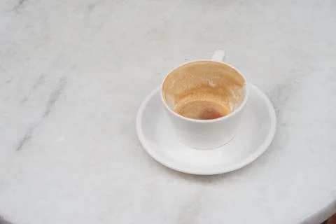 Cup sits empty on a white table after enjoying coffee Stock Photos
