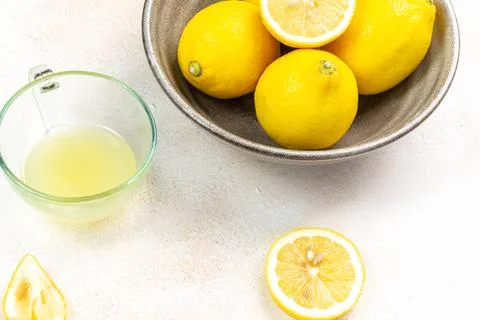 A cup of squeezed lemon juice and lemons, slices of lemons around. Bright b.. Stock Photos