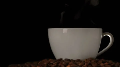 Cup of steaming coffee and coffee beans over dark background Stock Footage 61803372