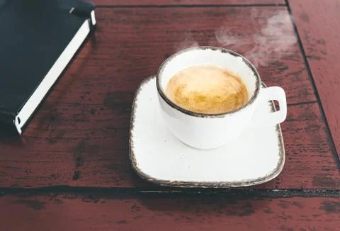 Cup of steaming hot espresso on rustic wooden desk Stock Photos