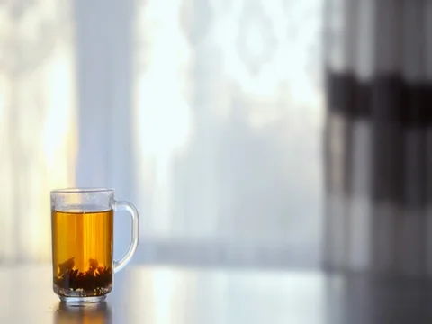 A Cup of steaming hot tea on the table against the window. Video stock 73976002