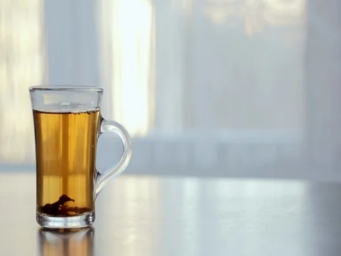 A Cup of steaming hot tea on the table against the window. Stock Footage 73976303