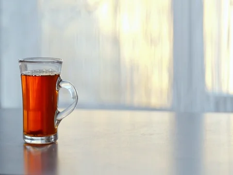 A Cup of steaming hot tea on the table against the window. 스톡 동영상 73976629