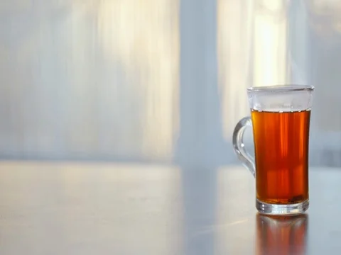A Cup of steaming hot tea on the table against the window. Stock Footage 73976963