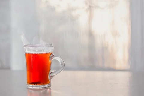 A Cup of steaming hot tea on the table against the window Фото