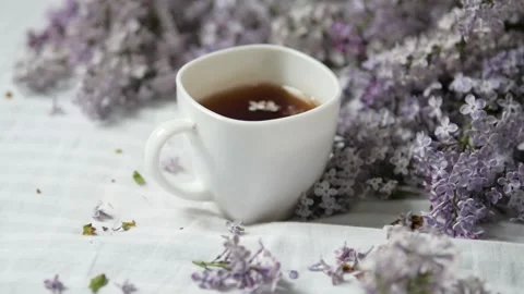 Cup of tea and branches of blooming lilacs on a white background. a cup of tea Stock Footage 148794757