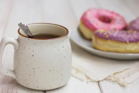 Cup of tea and fresh donuts in the white plate on wooden background Stock Photos