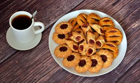 A cup of tea and a large assortment of shortbread cookies with fruit jam in.. Stock Photos