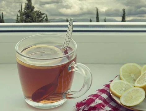 A Cup of tea and a lemon on the window sill On the windowsill is a Cup of ... Fotos Stock