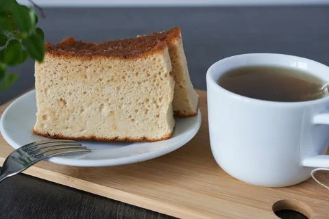 A cup of tea and a slice of castella muffin on a wooden board, selective focus. Stock Photos
