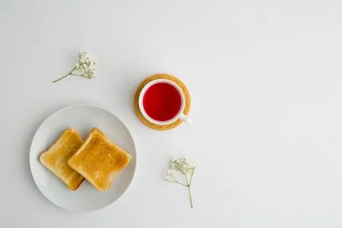 Cup of tea and toasted bread with small white flowers Stock Photos
