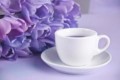 A cup of tea and violet tulips on the table Foto stock