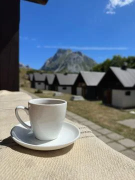 A cup of tea on the background of mountain and the cottage village Stock Photos