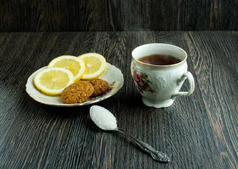 Cup of tea with biscuits and lemon on top, hot tea with lemon and sugar Stock Photos