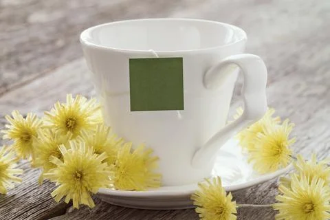 Cup of tea with blank tag and summer flowers on wooden background Stock Photos