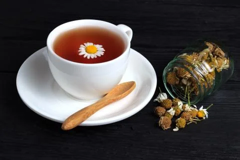 Cup of tea with chamomile in a white cup on a black background Stock Photos