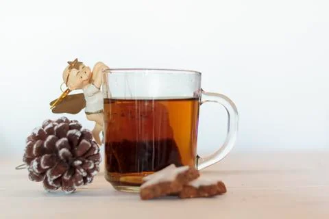 Cup of tea decorated with sweet angel, pine cone and cookies on white wooden  Stock Photos