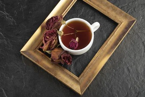 A cup of tea with dried rose and frame on a black background Stock Photos