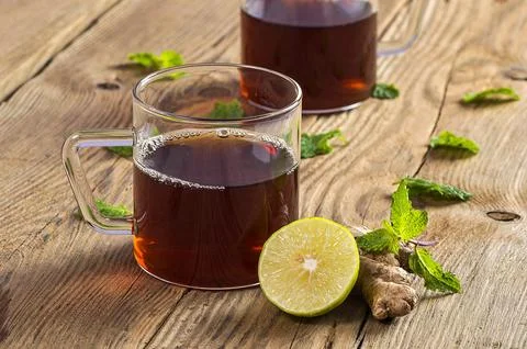 Cup of tea with ginger, lemon and mint on wooden table Stock Photos