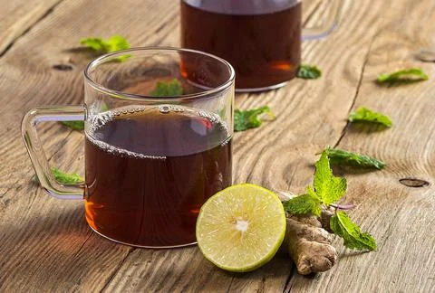 Cup of tea with ginger, lemon and mint on wooden table Stock Photos