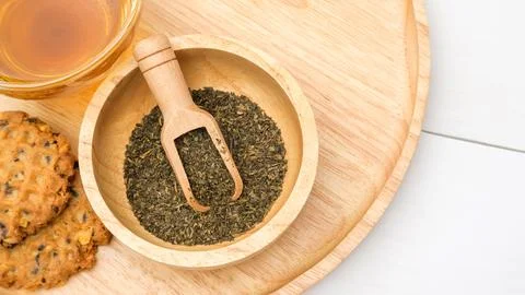 A cup of tea, green tea leaf, and cookie on a table. Stock Photos