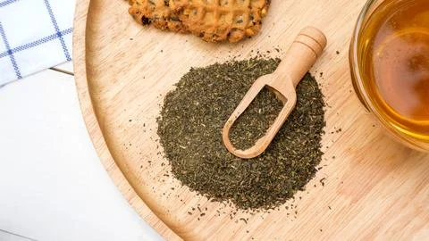 A cup of tea, green tea leaf, and cookie on a table. Stock Photos