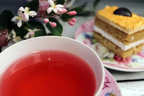 A cup of tea large smooth and a cake on a wooden table with flowers in the Stock Photos