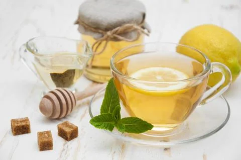 A cup of tea with lemon, mint and honey on wooden white background Stock Photos