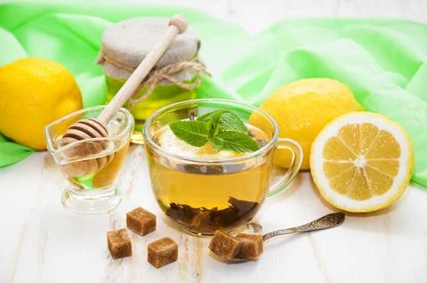 A cup of tea with lemon, mint and honey on wooden white background Stock Photos