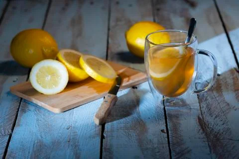 Cup of tea with a lemon slice next to a cutting board with a sliced lemon and a Stock Photos
