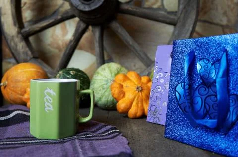 A Cup of tea on a lilac bedspread, on a table with pumpkins and a cart wheel Foto stock