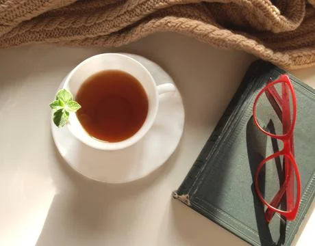 Cup of tea with mint, book and glasses. Stock Photos
