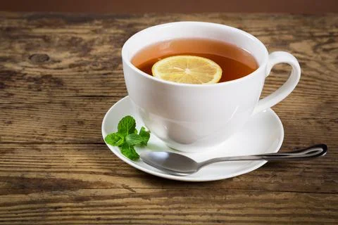 Cup of tea with mint leaf and lemon slice on old wooden desk, empty space f.. Stock Photos