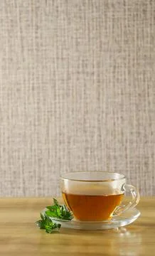 Cup of tea with mint leaves placed on a wooden table near a textured background 库存照片