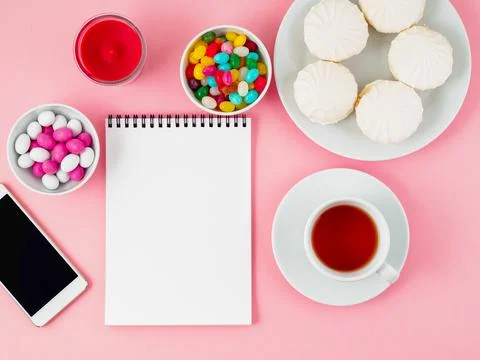 Cup of tea, notepad, mobile and plates of different sweets - marshmallows Stock Photos