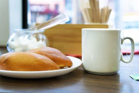 A Cup of tea with a pie on the table by the window in the cafe. Stock Photos