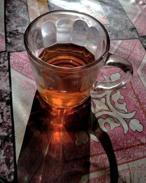Cup of tea is placed on a table with a pink and white patterned cloth. Stock Photos