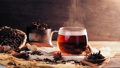A cup of tea is placed on a wooden table with hot steam in slow motion. The dark Stock Footage 202159536