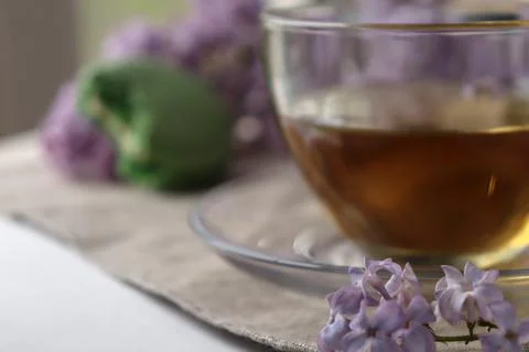 Cup of tea sits on a table with flowers and a soft background creating a cozy 스톡 사진