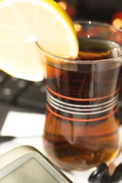 A Cup of tea with a slice of lemon on the background of laptop Stock Photos