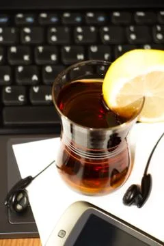 A Cup of tea with a slice of lemon on the background of laptop Stock Photos
