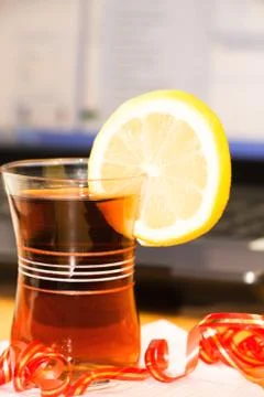 A Cup of tea with a slice of lemon on the background of laptop Stock Photos