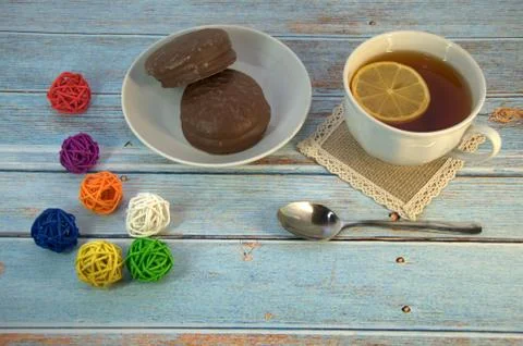 A cup of tea with a slice of lemon, a spoon and a plate of chocolate cake lie Stock Photos