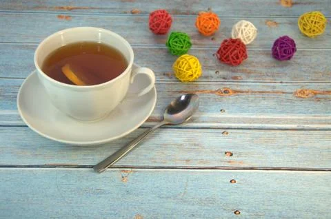 A cup of tea with a slice of lison and a spoon lie on a wooden table with a d Stock Photos