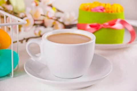 A cup of tea, small spring cake, flowers sakura, colorful eggs for Easter day Stock Photos