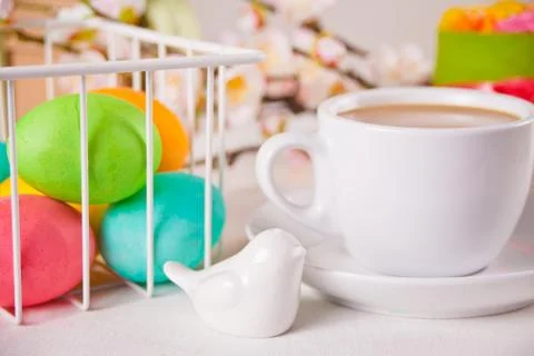 A cup of tea, small spring cake, flowers sakura, colorful eggs for Easter day Stock Photos