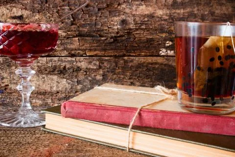 Cup of tea on a stack of books next to a rope tied to jam in a vase Foto stock
