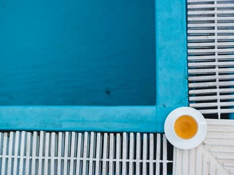 A cup of tea stands in a corner on the edge of a pool with blue water, shot f Stock Photos