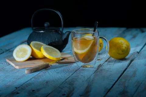 Cup of tea surrounded by a cutting board with a sliced lemon, some whole lemons Stock Photos