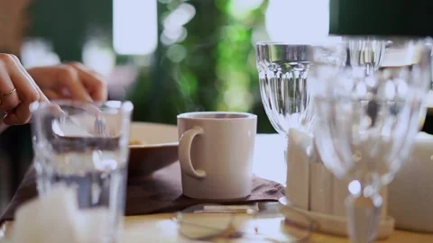 Cup of tea on table man eating breakfast in cafe Stock Footage 200775051